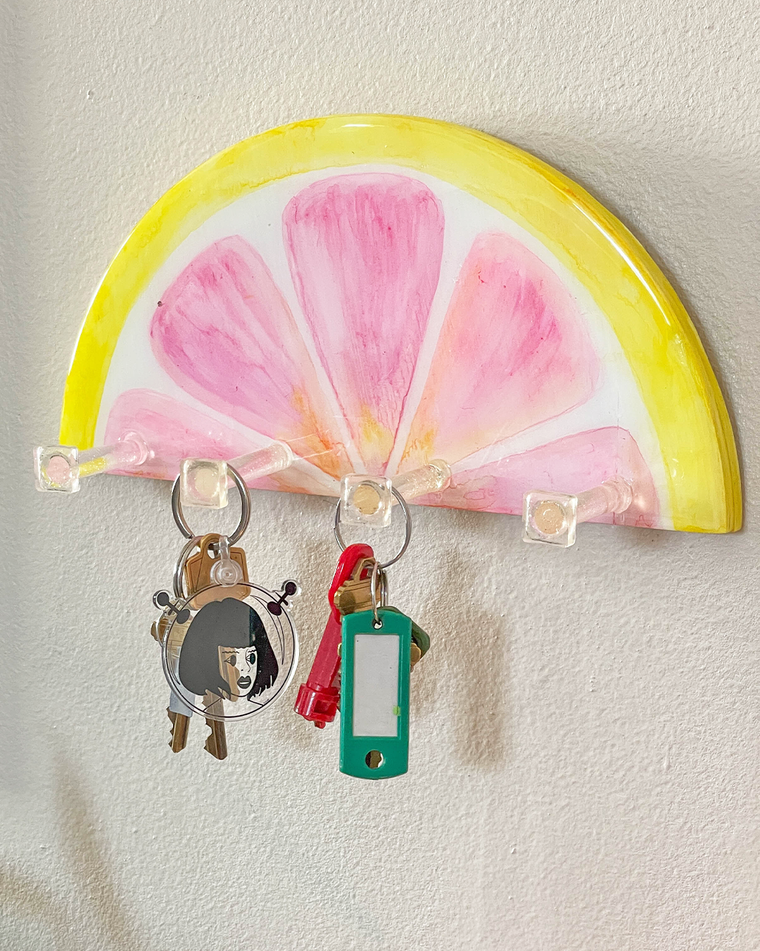 Innovative and artistic key holder resembling a slice of pink grapefruit on a wall.