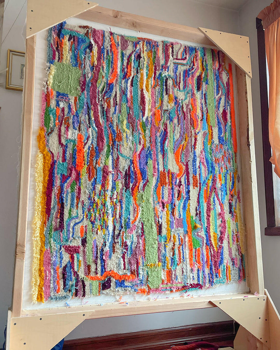 A colorful tufted rug made entirely of scraps of yarn that were leftover from prior rug projects.